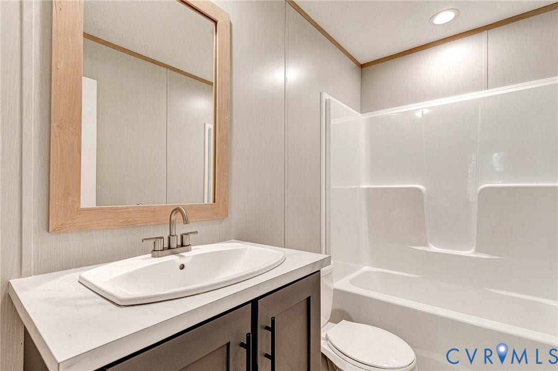 15263 Cross County Road, Mineral, VA 23117 Bathroom featuring a light wood-finish framed mirror, white oval sink basin, and a chrome faucet