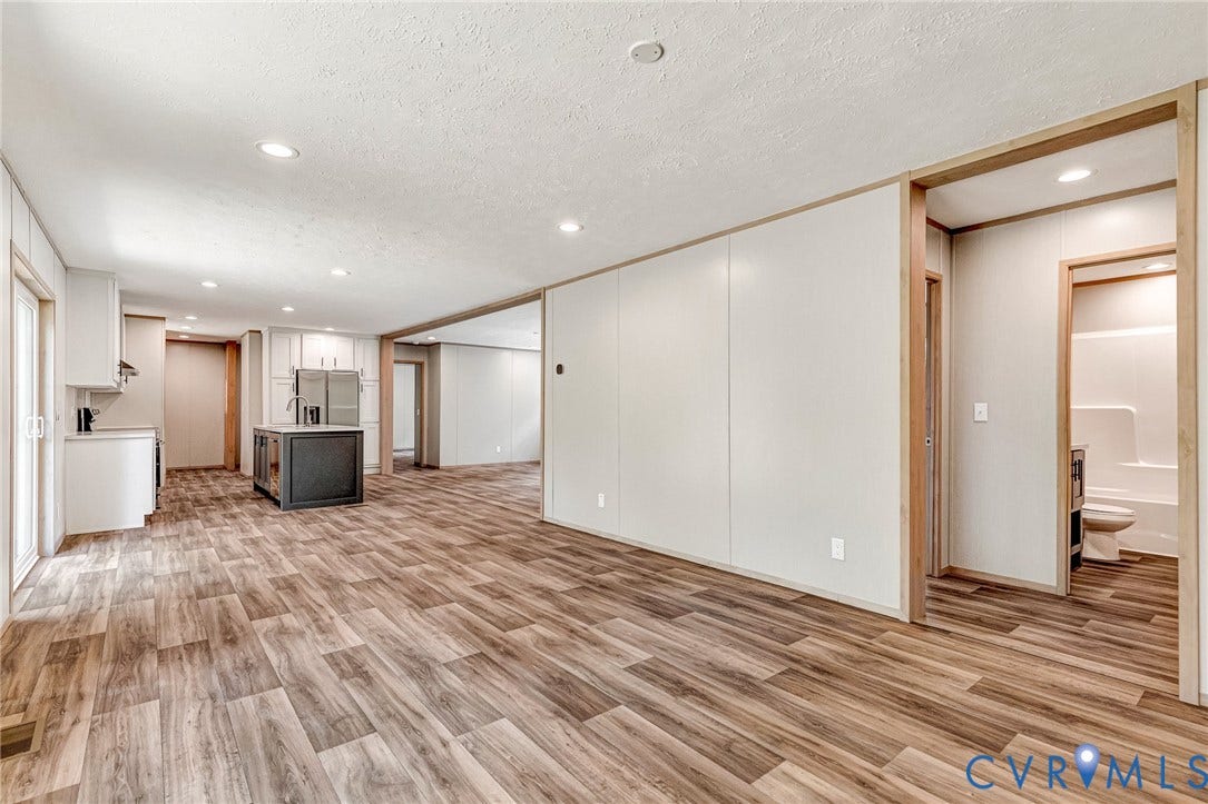 15263 Cross County Road, Mineral, VA 23117 Spacious open-concept interior featuring wood-finish flooring, recessed lighting, white cabinetry, a kitchen island with a dark countertop, and stainless steel appliances