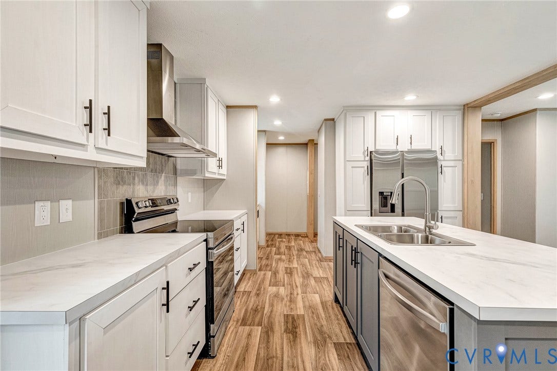 15263 Cross County Road, Mineral, VA 23117 Kitchen featuring white upper cabinetry, stainless steel appliances, wood-finish flooring, a center island with a double sink, and light-toned countertops