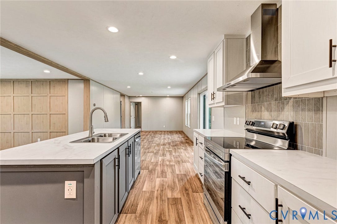 15263 Cross County Road, Mineral, VA 23117 Contemporary kitchen featuring an island with a double basin sink, stainless steel appliances, white cabinetry, and wood-finish flooring
