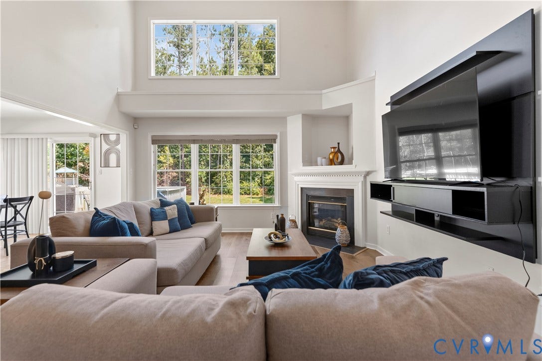 Family room with two-story ceiling and wall of windows.