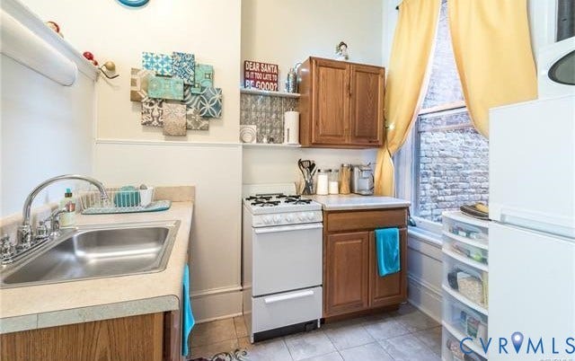 1524 Grove Avenue, Richmond, VA 23220 Compact kitchen featuring a stainless steel sink, laminate countertops, a gas range, and wood-finish cabinetry