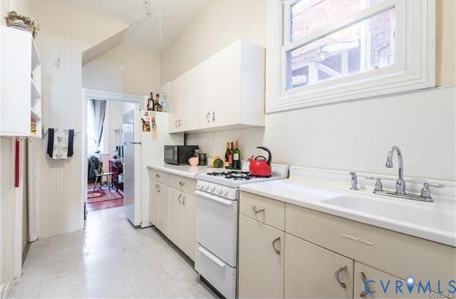 1524 Grove Avenue, Richmond, VA 23220 White cabinetry, white countertop, white gas range, and a single basin sink with a chrome faucet