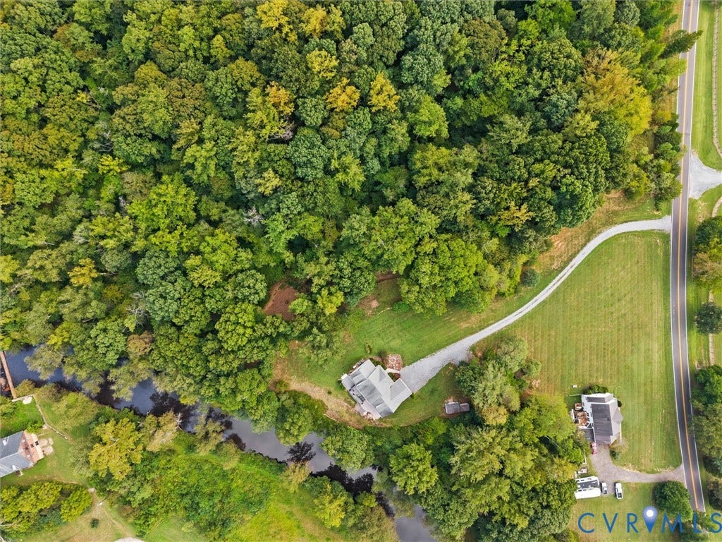 6126 Cartersville Road, Powhatan, VA 23139 Expansive wooded acreage featuring a meandering waterway, a single-story residence with a gray roof, and a gravel driveway