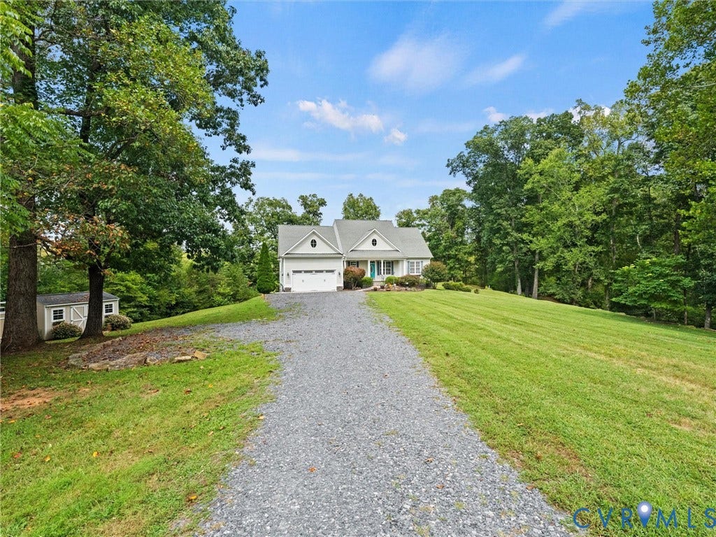6126 Cartersville Road, Powhatan, VA 23139 Gravel driveway leading to a residence with a two-car garage, surrounded by mature trees and a manicured lawn