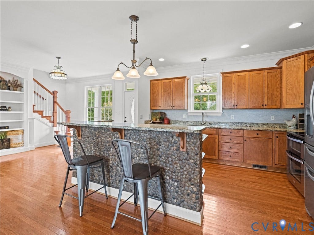 6126 Cartersville Road, Powhatan, VA 23139 Wood-finish flooring throughout, stone-clad kitchen island with solid surface countertop, built-in cabinetry, stainless steel appliances, and a staircase with wood handrails