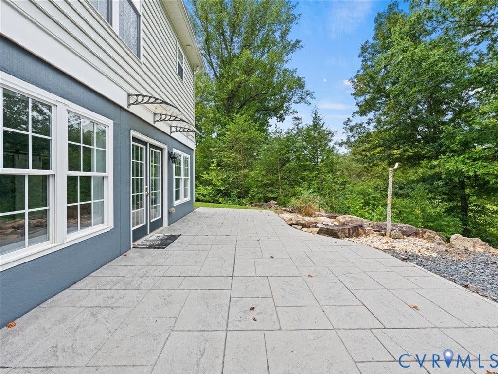 6126 Cartersville Road, Powhatan, VA 23139 Expansive stone patio with French doors, multiple windows, and a landscaped rock border
