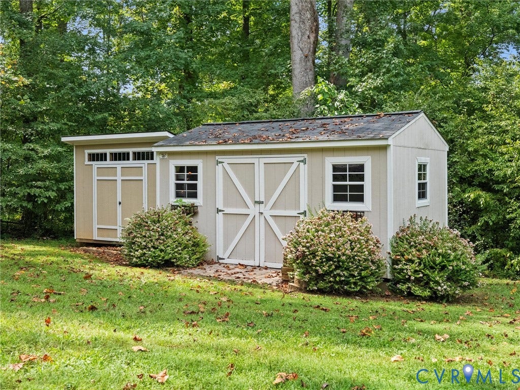 6126 Cartersville Road, Powhatan, VA 23139 Detached shed with an extended lean-to, multiple windows, and dual entry doors, set against a wooded backdrop