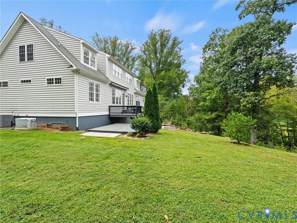 6126 Cartersville Road, Powhatan, VA 23139 Siding exterior with multiple windows, leading to a dark-toned deck and a lower concrete patio