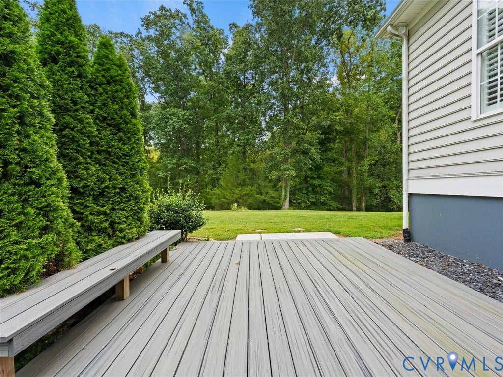 6126 Cartersville Road, Powhatan, VA 23139 Spacious backyard deck with composite decking, integrated bench seating, mature evergreen plantings, and a manicured lawn