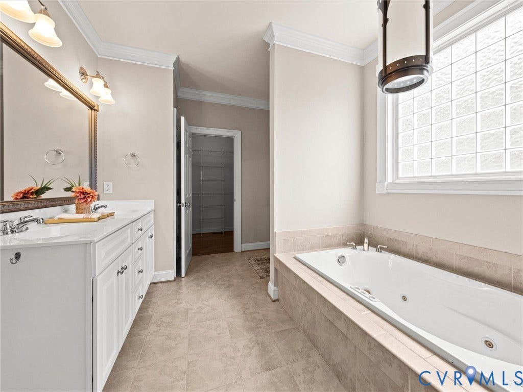 6126 Cartersville Road, Powhatan, VA 23139 Dual vanity with white cabinetry and integrated sinks, a built-in jetted tub with tile surround, a glass block window, and tile flooring