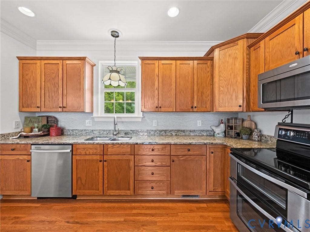 6126 Cartersville Road, Powhatan, VA 23139 Wood-finish cabinetry with stainless steel appliances, granite-style countertops, and a tile backsplash