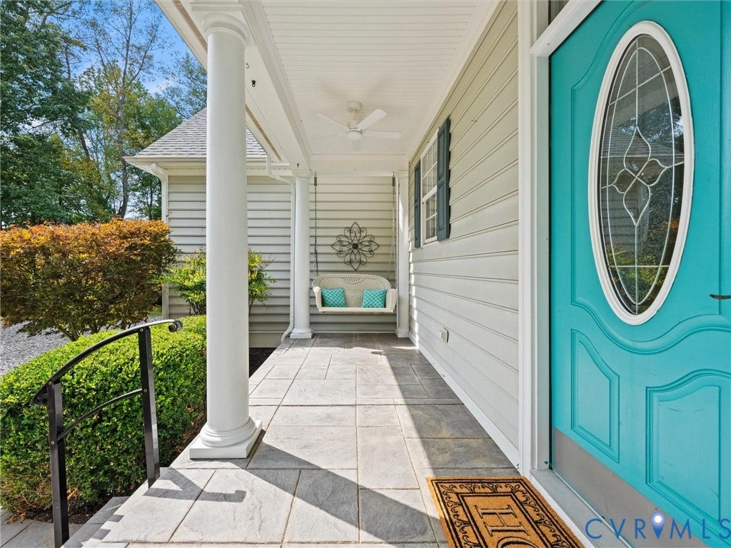 6126 Cartersville Road, Powhatan, VA 23139 Covered front porch featuring a decorative ceiling fan, a teal front door with an oval leaded glass insert, gray tile flooring, and a white support column
