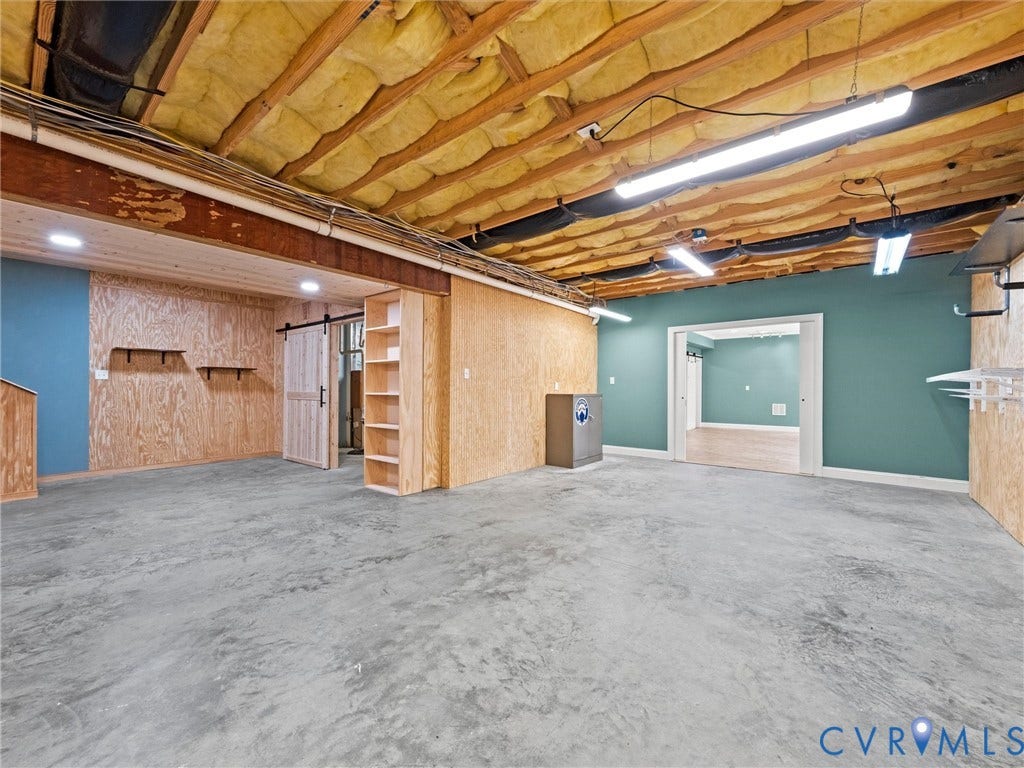 6126 Cartersville Road, Powhatan, VA 23139 Unfinished basement space featuring exposed ceiling joists, concrete flooring, and a barn door entry
