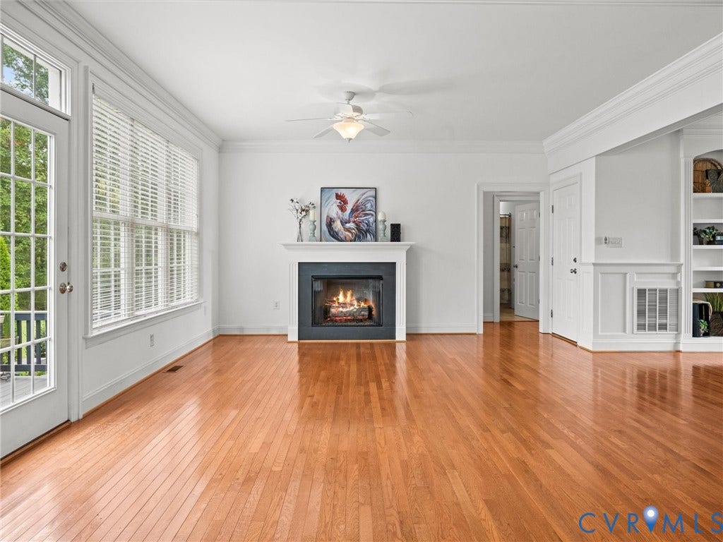 6126 Cartersville Road, Powhatan, VA 23139 Wood-finish flooring, white fireplace with a dark surround, white crown molding, a built-in shelving unit, and a ceiling fan
