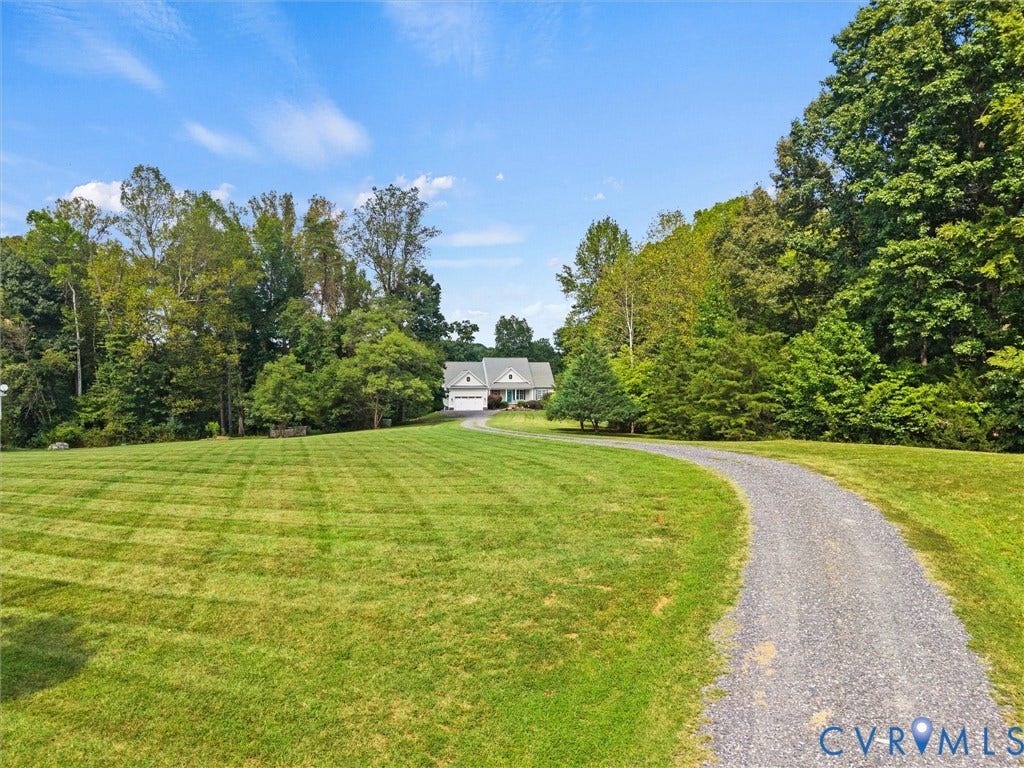 6126 Cartersville Road, Powhatan, VA 23139 Gravel driveway with a large grassy area, surrounded by mature trees