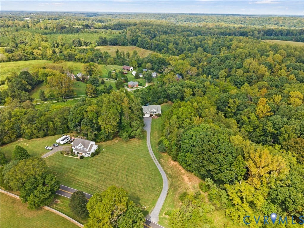 6126 Cartersville Road, Powhatan, VA 23139 Expansive property with a verdant landscape, featuring two distinct residences, a paved road, and a gravel driveway, all surrounded by dense mature trees