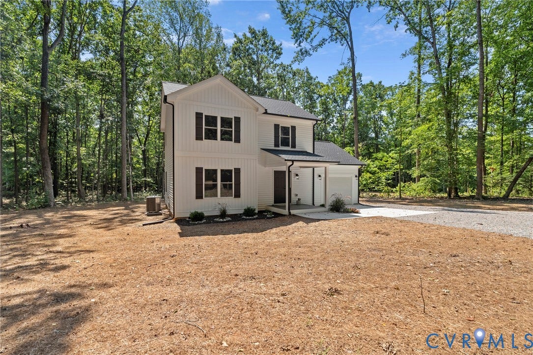 6465 Anderson Highway, Powhatan, VA 23139 Two-story residence featuring white board and batten siding, dark shutters, an attached two-car garage, and a gravel driveway