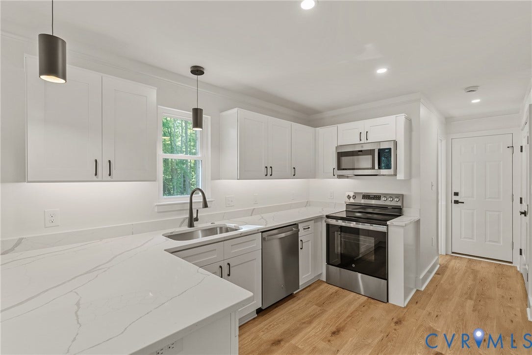 6465 Anderson Highway, Powhatan, VA 23139 White cabinetry with black hardware, white countertops with veining, stainless steel appliances, wood-finish flooring, and recessed lighting