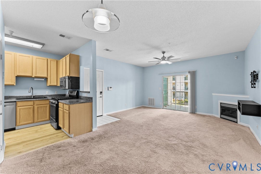 821 Brassie Lane, #E, The Crossings Golf Course Area, Glen Allen, VA 23059 Kitchen featuring light-finish cabinetry, stone-texture countertops, and stainless steel appliances, supplemented by a built-in fireplace, ceiling fan, and sliding glass door