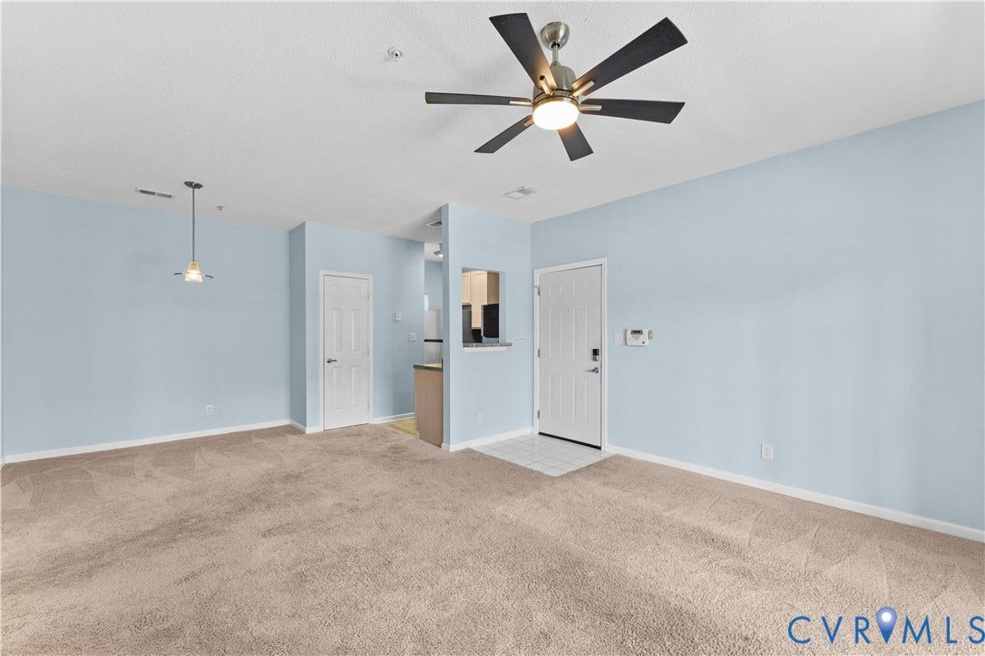 821 Brassie Lane, #E, The Crossings Golf Course Area, Glen Allen, VA 23059 Living area featuring neutral carpeting, a central multi-blade ceiling fan with integrated lighting, a pendant fixture, and a pass-through opening to the kitchen