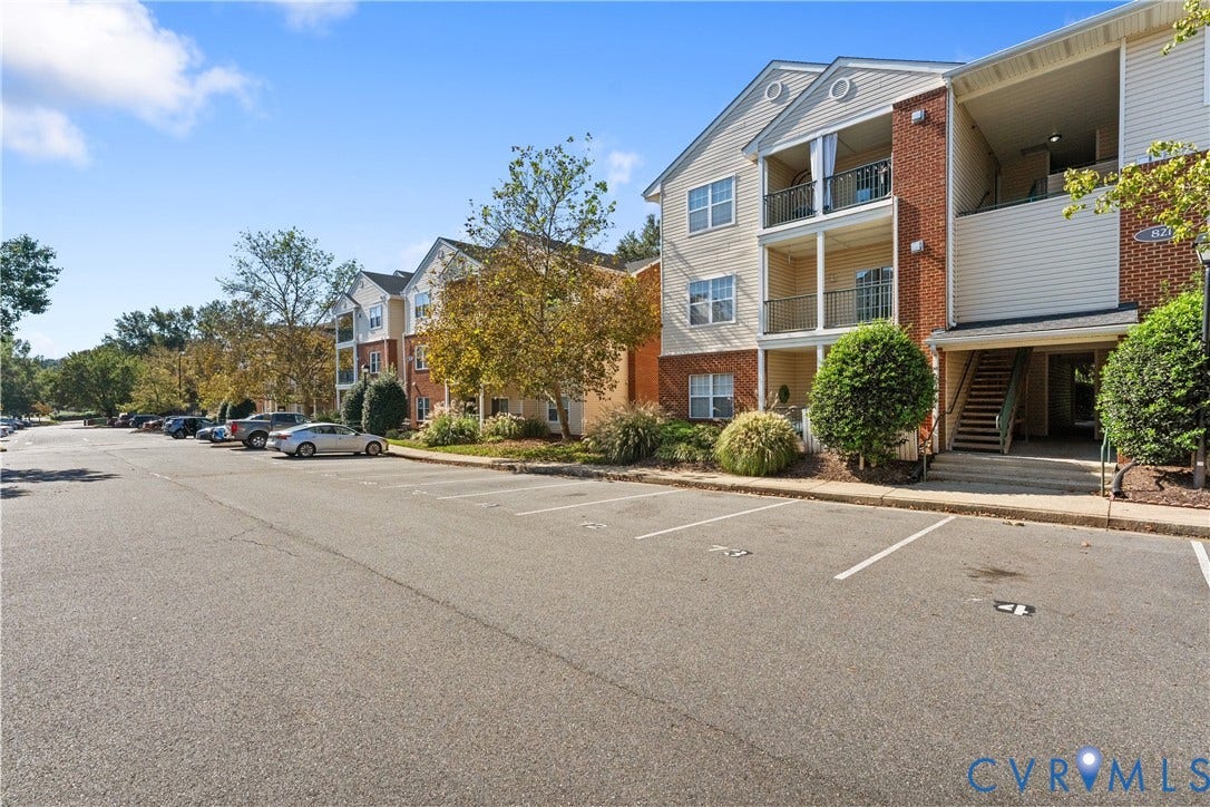 821 Brassie Lane, #E, The Crossings Golf Course Area, Glen Allen, VA 23059 Multi-story residential building featuring brick and vinyl siding, private covered balconies with metal railings, and dedicated surface parking