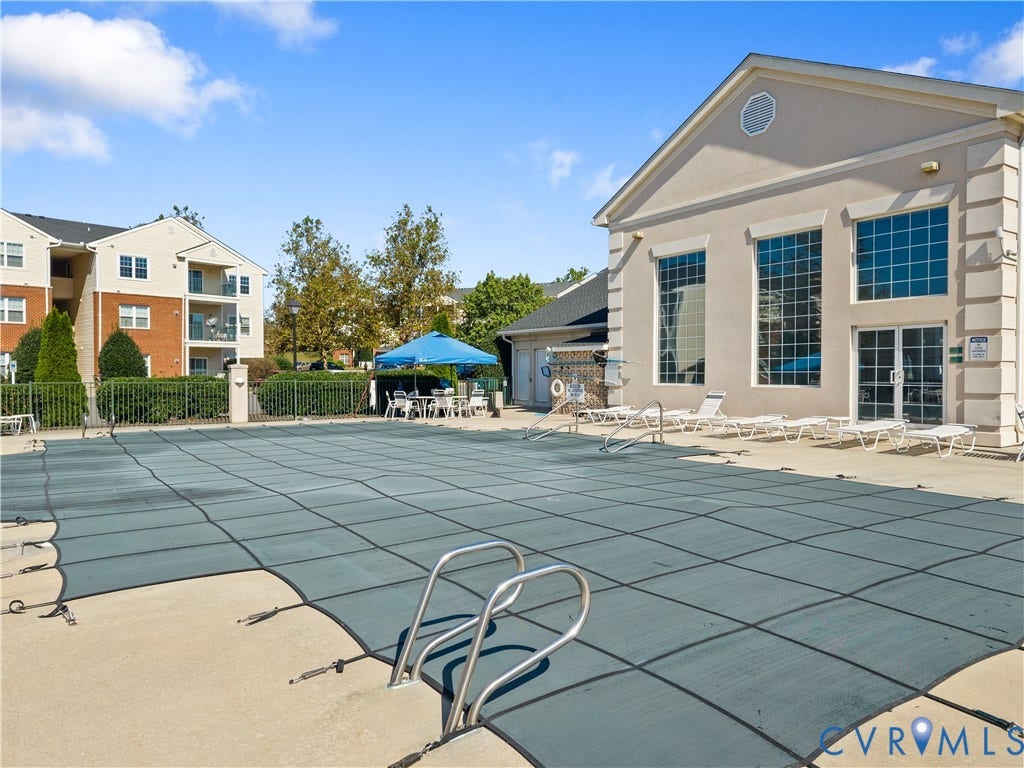 821 Brassie Lane, #E, The Crossings Golf Course Area, Glen Allen, VA 23059 Swimming pool with a fitted safety cover, concrete decking, and multi-story clubhouse featuring large-pane windows and a pediment roofline