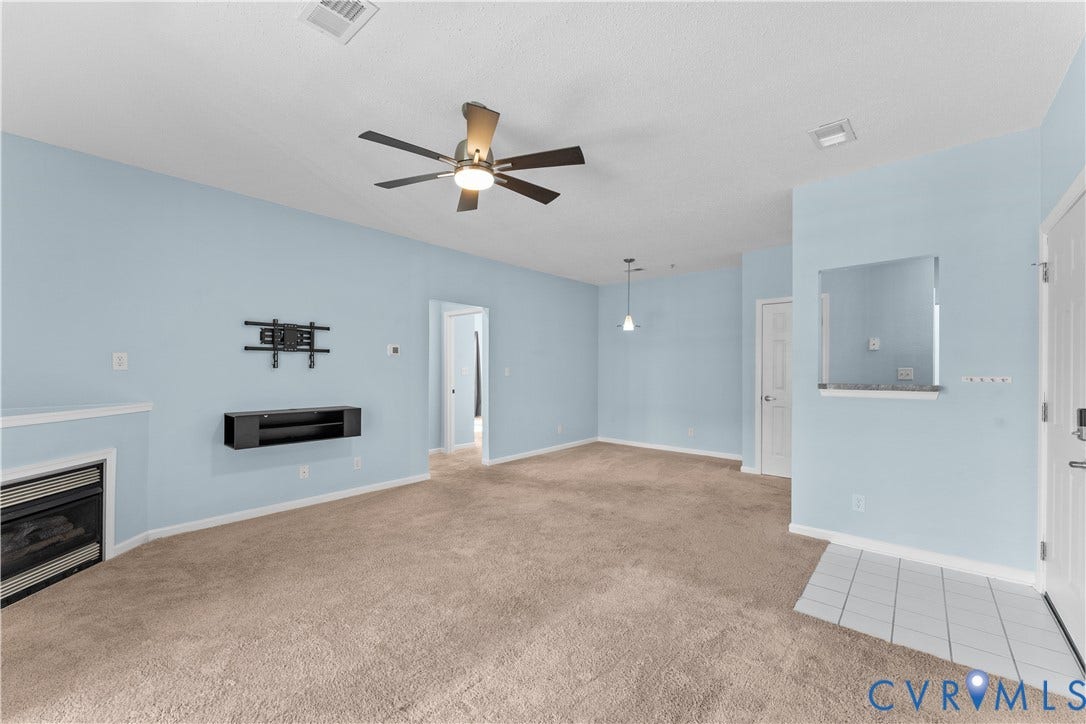 821 Brassie Lane, #E, The Crossings Golf Course Area, Glen Allen, VA 23059 Gas fireplace with a stone surround, neutral carpeting, ceiling fan with integrated lighting, tiled entryway, and wall-mounted cabinetry
