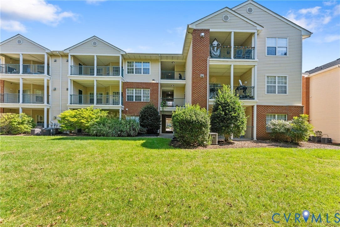 821 Brassie Lane, #E, The Crossings Golf Course Area, Glen Allen, VA 23059 Multi-story building exterior featuring vinyl siding, brick masonry detailing, private covered balconies with metal railings, and an expansive lawn