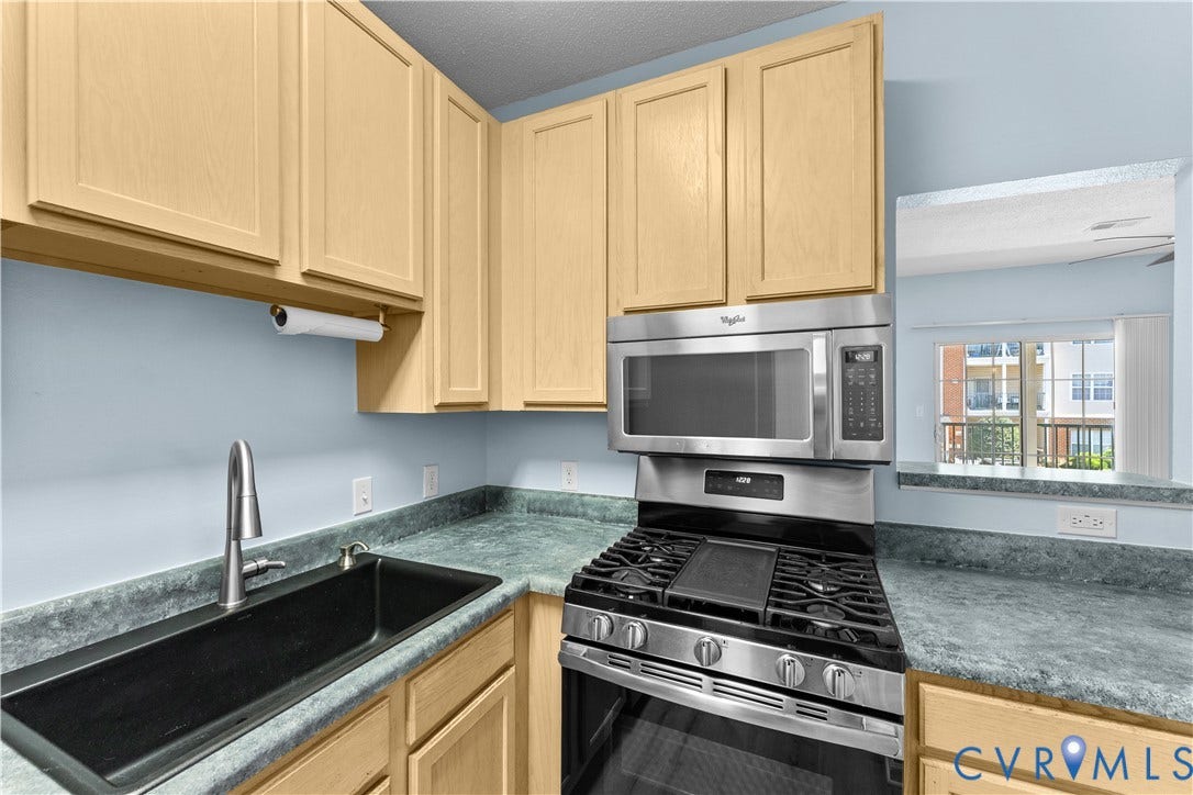821 Brassie Lane, #E, The Crossings Golf Course Area, Glen Allen, VA 23059 Kitchen featuring light-finish cabinetry, a black undermount sink with a high-arc faucet, solid-surface countertops, and stainless steel appliances including a gas range and over-the-range microwave