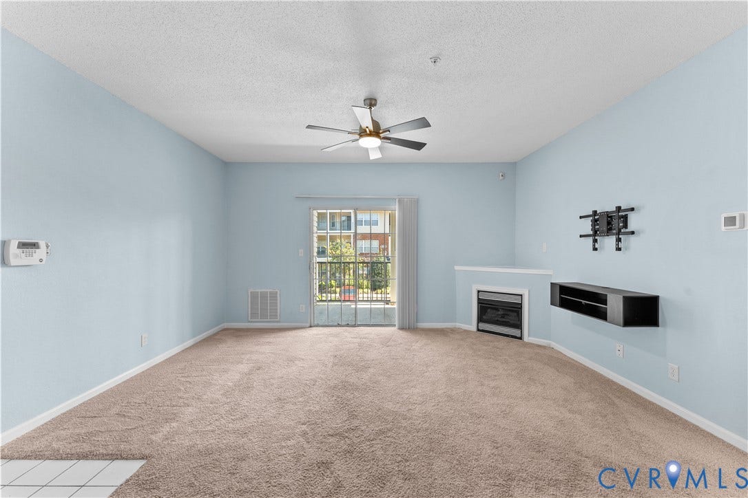821 Brassie Lane, #E, The Crossings Golf Course Area, Glen Allen, VA 23059 Living area featuring wall-to-wall carpeting, ceiling fan, sliding glass door, fireplace with mantel, and wall-mounted shelving