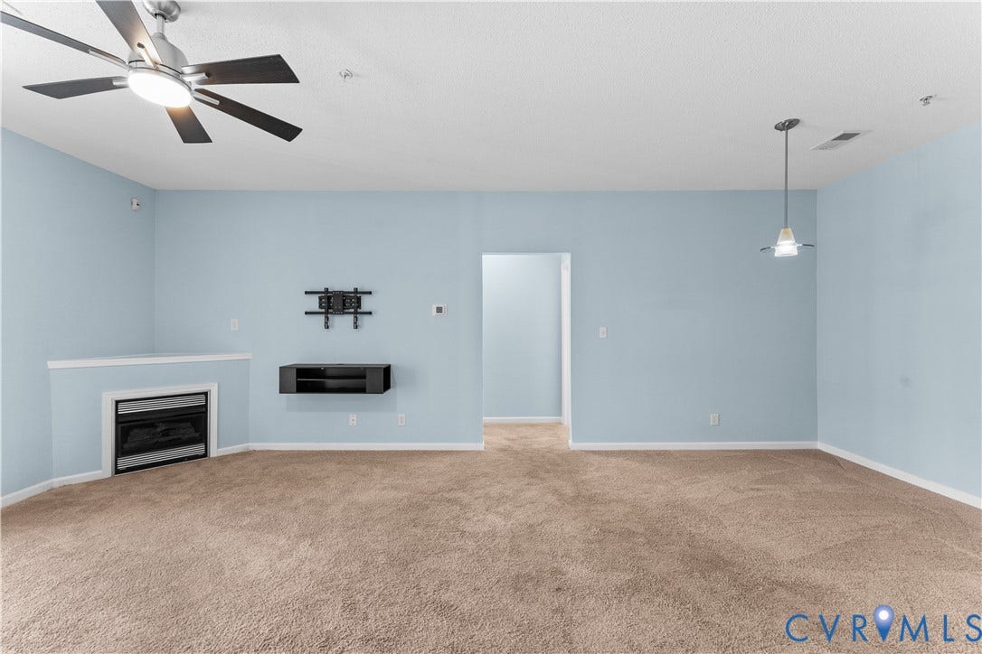 821 Brassie Lane, #E, The Crossings Golf Course Area, Glen Allen, VA 23059 Interior space featuring a corner fireplace with a mantel, wall-mounted console, ceiling fan with light fixture, pendant lighting, and neutral carpeting