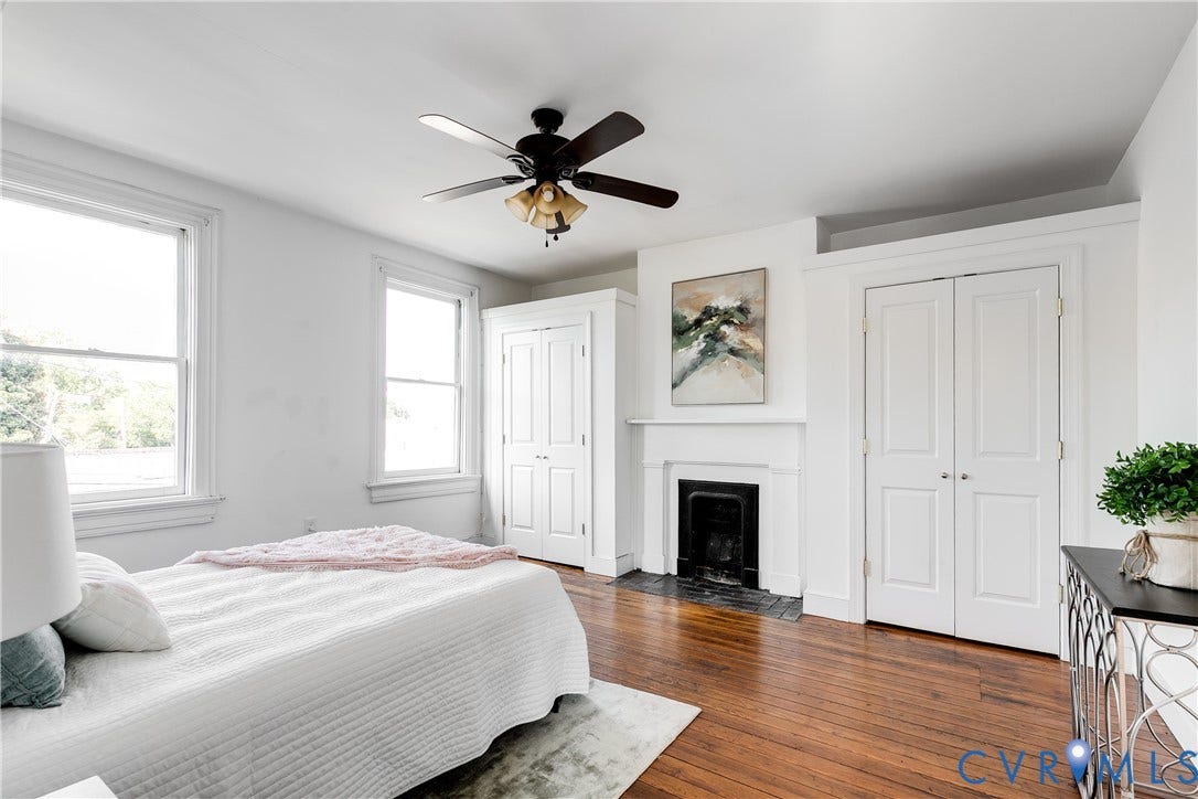 2216 E Marshall Street, Church Hill North, Richmond, VA 23223 Hardwood flooring, two large windows, ceiling fan with integrated lighting, decorative fireplace with mantel, and built-in closet storage