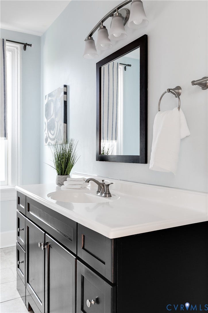 2216 E Marshall Street, Church Hill North, Richmond, VA 23223 Dark wood finish vanity with integrated white countertop sink, brushed nickel faucet, and coordinating wall-mounted light fixture