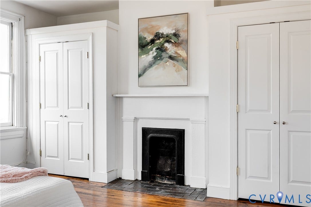 2216 E Marshall Street, Church Hill North, Richmond, VA 23223 White fireplace mantel with a black iron firebox, flanked by two built-in storage closets with bi-fold paneled doors