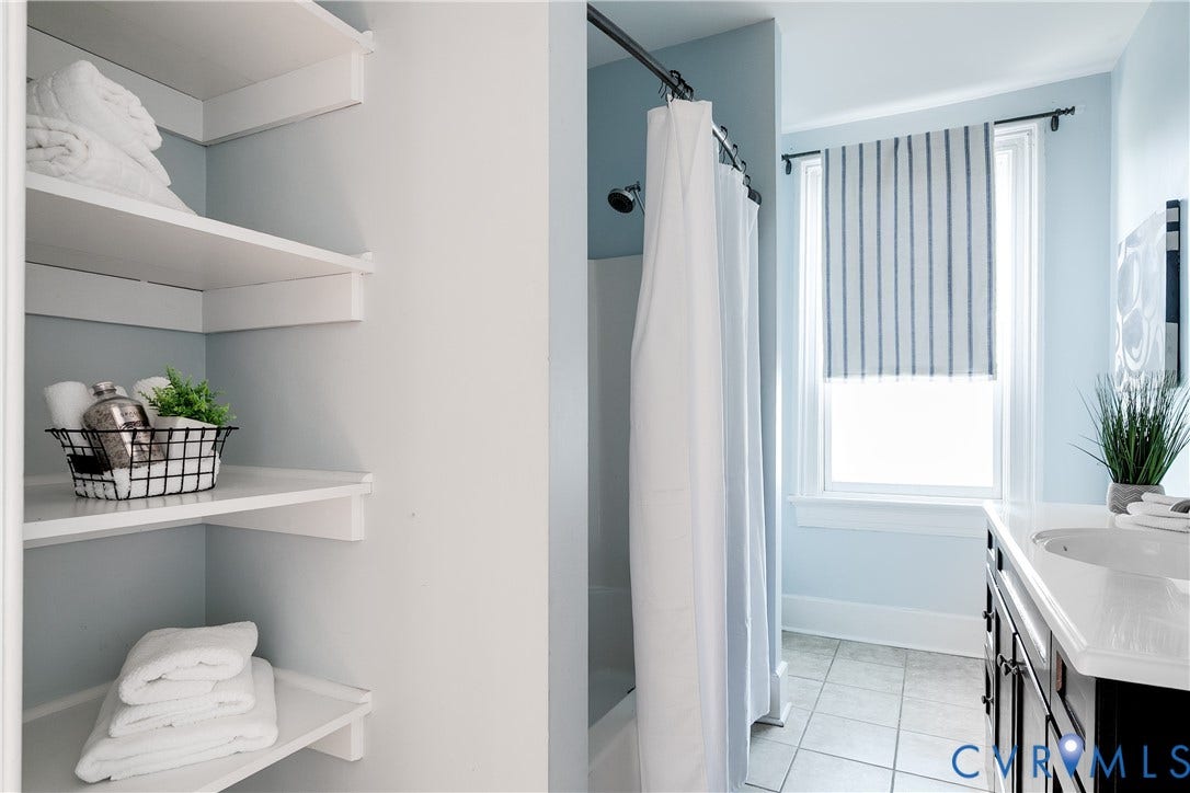 2216 E Marshall Street, Church Hill North, Richmond, VA 23223 Built-in shelving, shower with white curtain, vanity with integrated sink, rectangular window, and tiled flooring