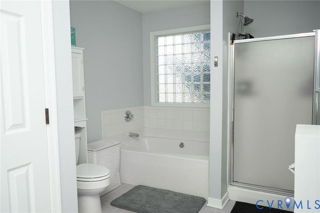 15349 Featherchase Drive, Chesterfield, VA 23832 Bathtub with white tile surround, glass block window, and adjacent shower with frosted glass enclosure