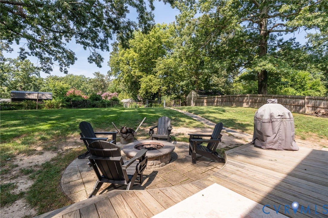 1204 Maywood Road, Beverly Hills, Henrico, VA 23229 Expansive backyard featuring a wood deck, a stone fire pit with paver surround, and a fenced perimeter