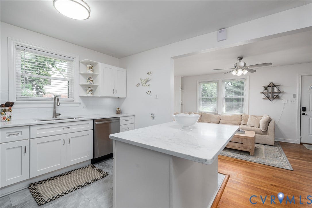 1204 Maywood Road, Beverly Hills, Henrico, VA 23229 White kitchen cabinetry, undermount sink with gooseneck faucet, light-toned countertop, stainless steel dishwasher, and wood-finish flooring in the adjacent room