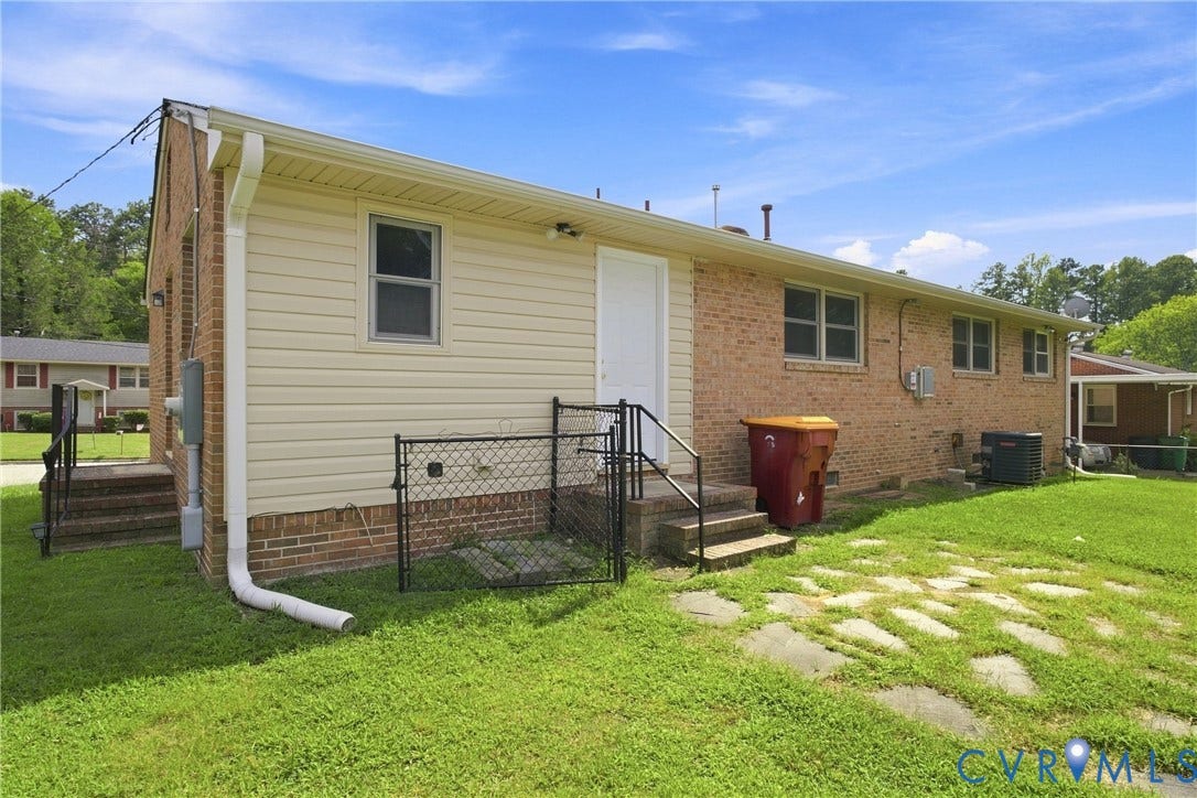 1721 S Halcun Drive, Petersburg, VA 23803 Brick and siding exterior with multiple windows, leading to a lawn with stepping stones