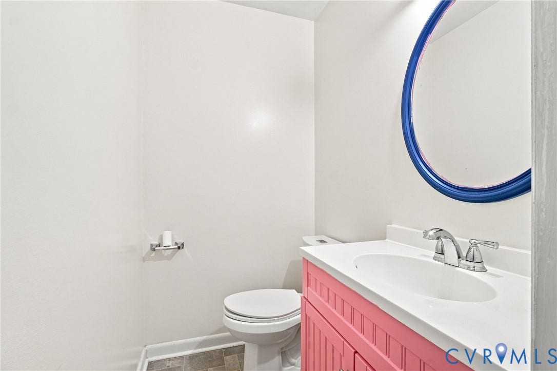 1721 S Halcun Drive, Petersburg, VA 23803 White vanity countertop with an integrated sink, chrome faucet, and a round wall mirror
