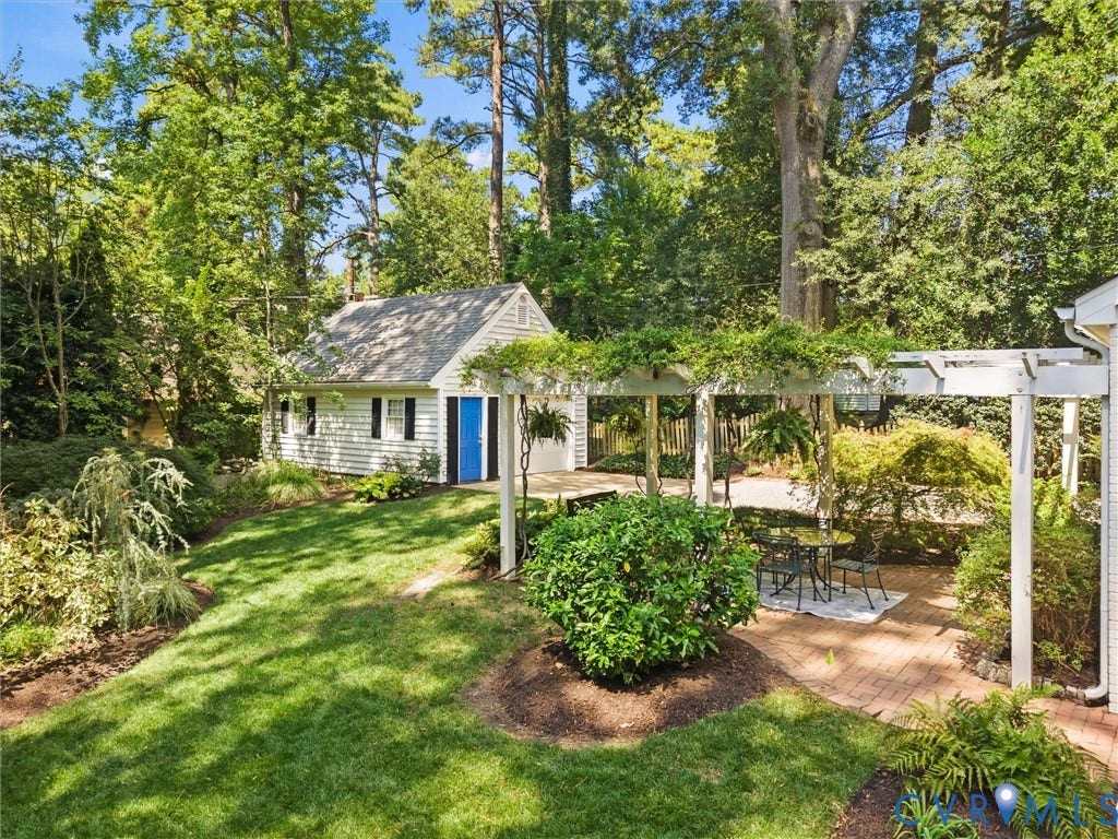 Manicured lawn with mature trees, brick patio, and white pergola