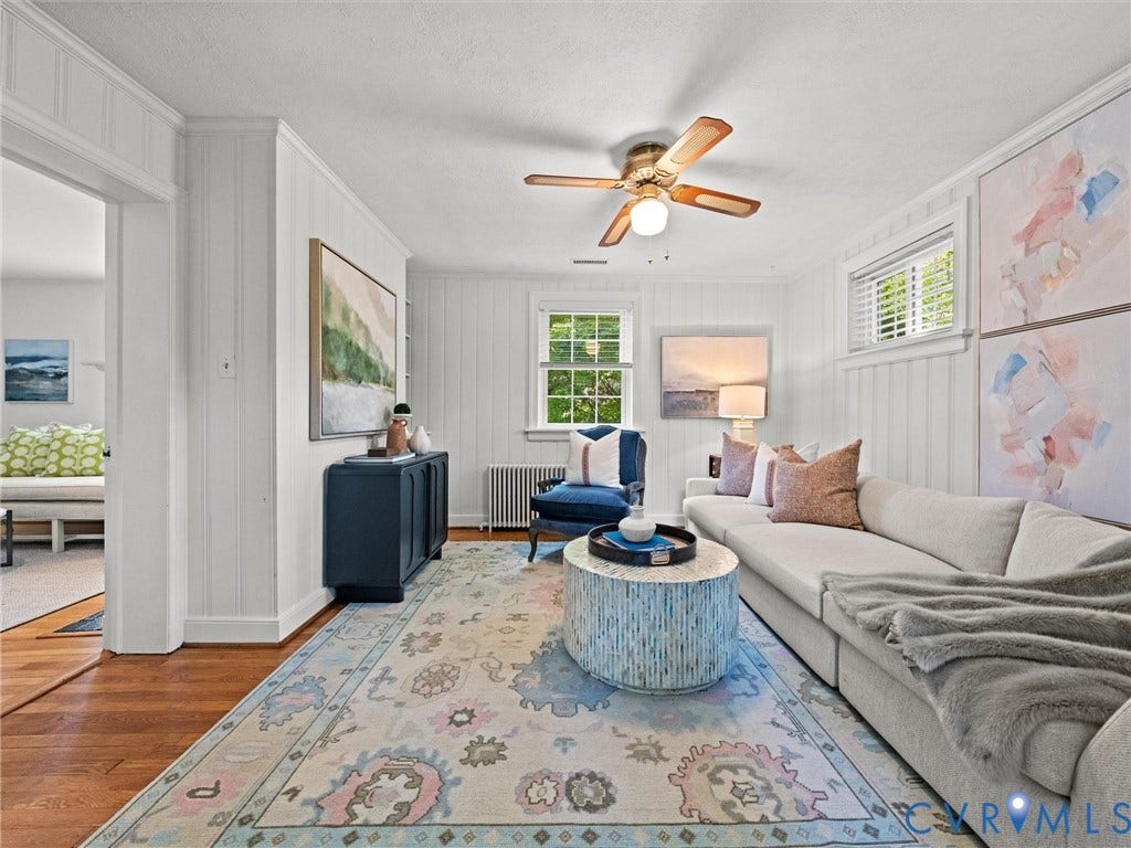 Wood-finish flooring, white paneled walls, ceiling fan, and window with blinds