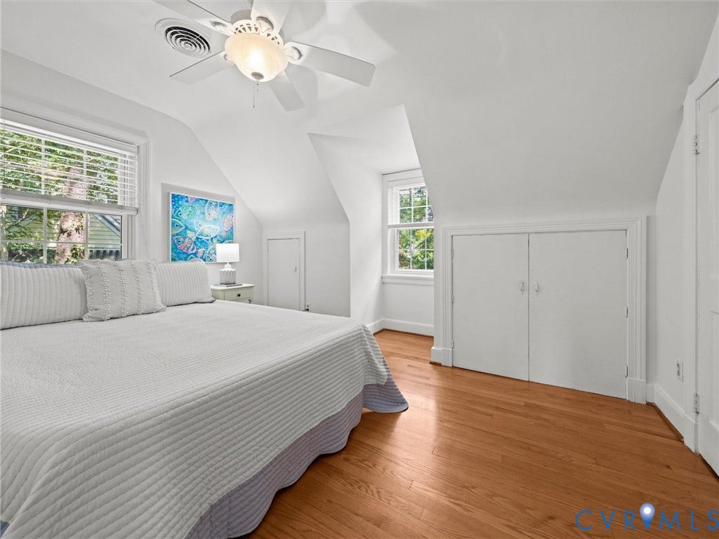 Wood-finish flooring, white walls, two windows with blinds, a ceiling fan with light, and built-in closet doors