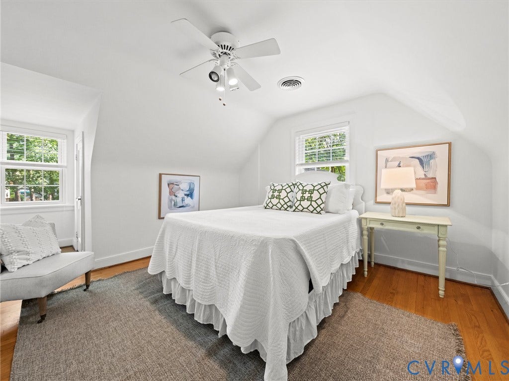 Attic room with sloped ceilings, hardwood flooring, and a ceiling fan