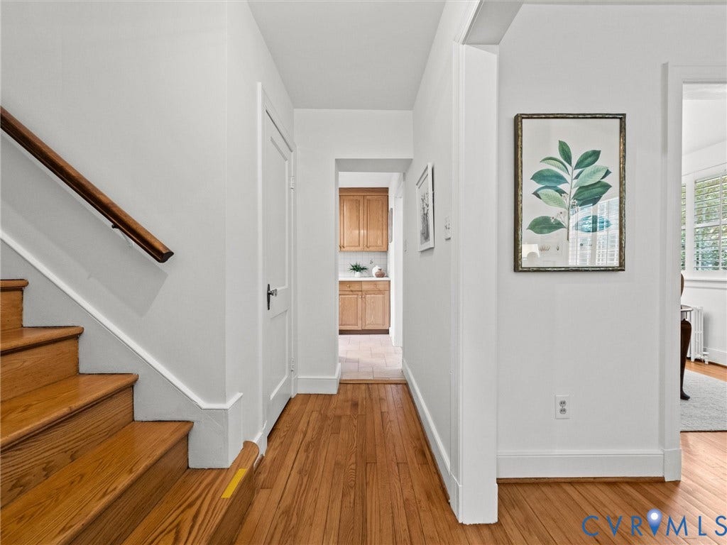 Hardwood staircase with a wood handrail, leading to a hallway with wood-finish flooring