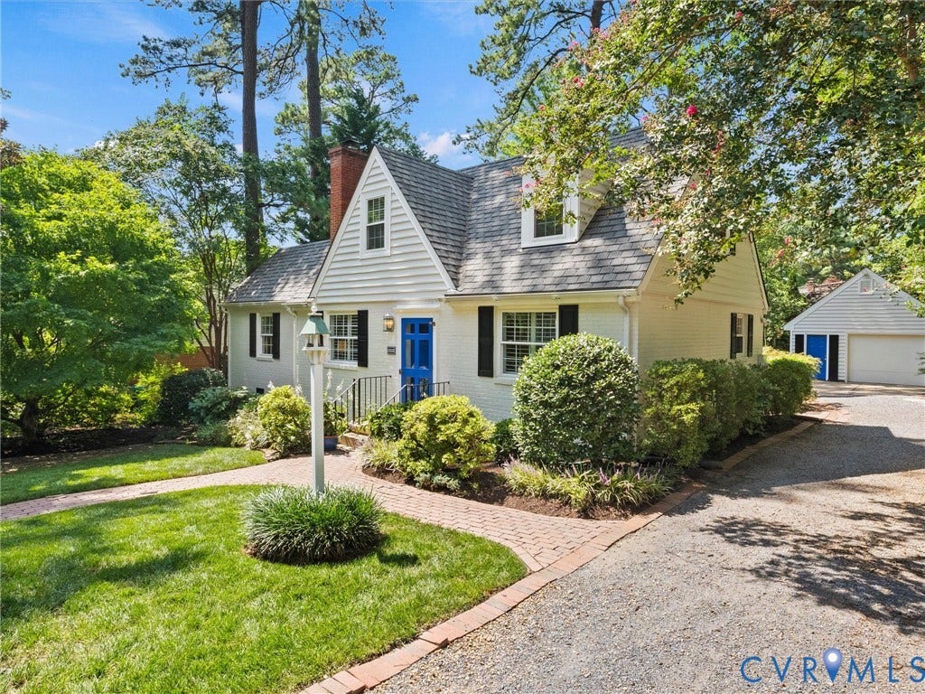 Gable roofline, white exterior siding, blue entry door, black shutters, and an attached two-car garage
