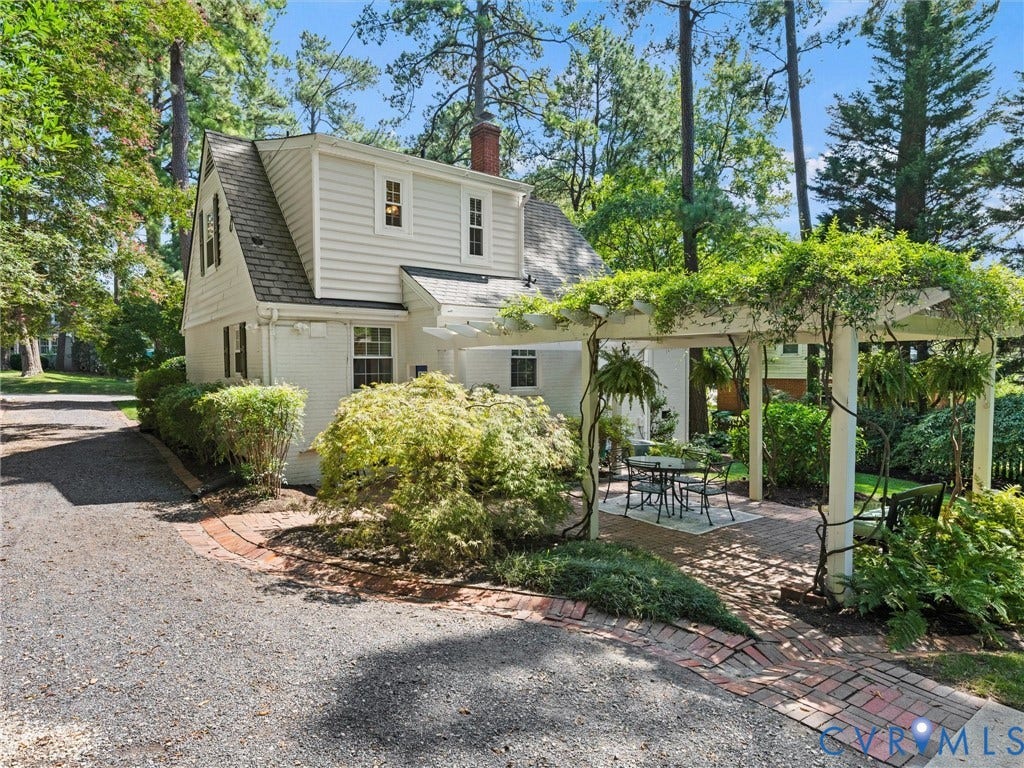 White siding exterior with a shingle roof, accompanied by a pergola-covered patio area