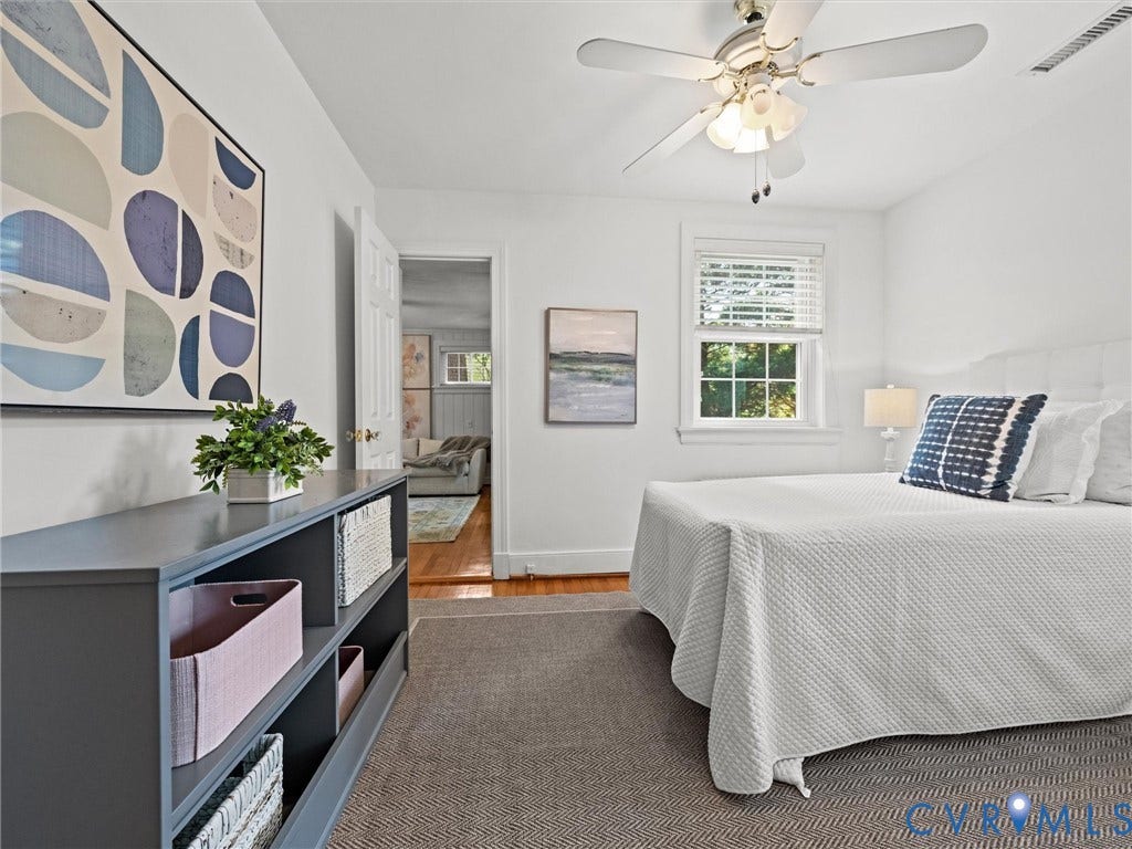 Bright interior space featuring a ceiling fan with integrated lighting, wood-finish flooring, and white window blinds