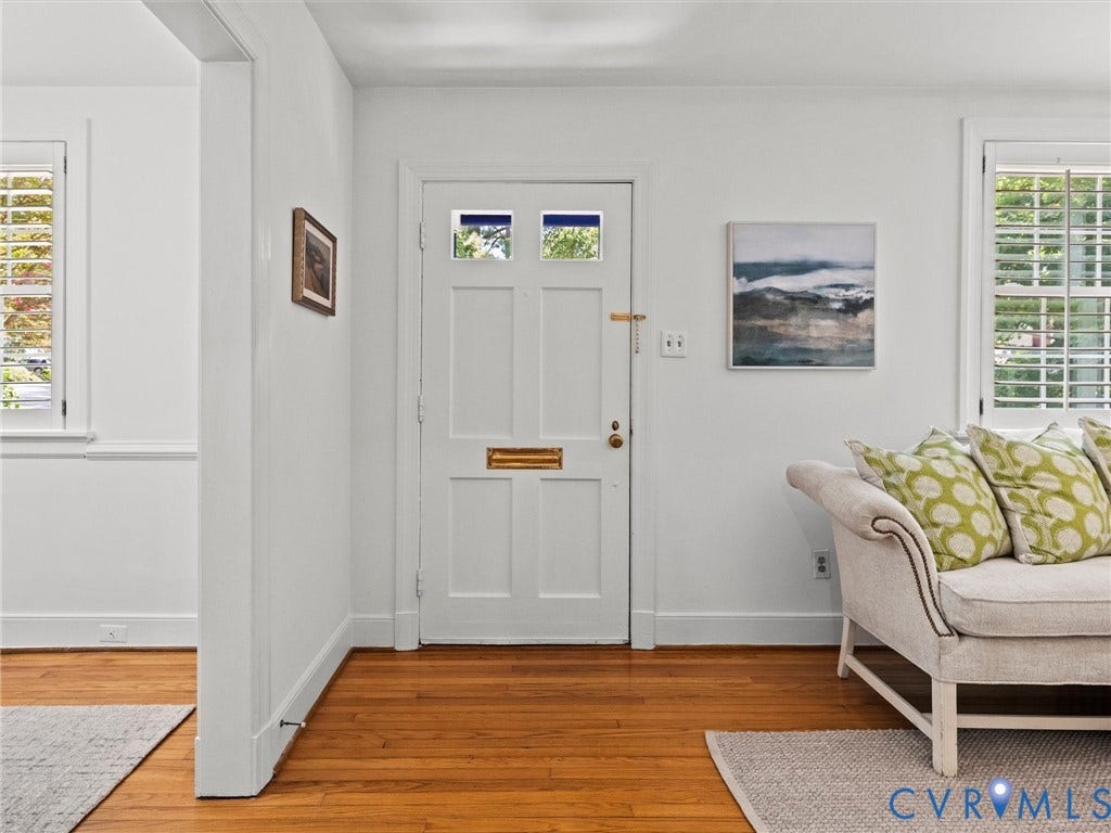 Hardwood flooring, white paneled door with glass inserts, and a window with plantation shutters